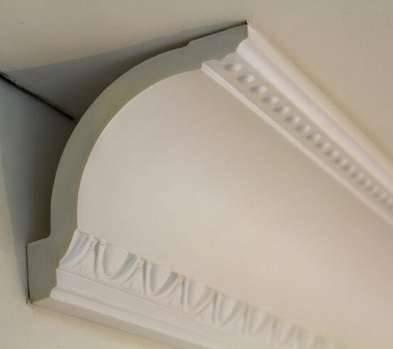Close-up detail of decoration white molding connected with glue adhesive to wall and ceiling in interior room renovation and reconstruction.