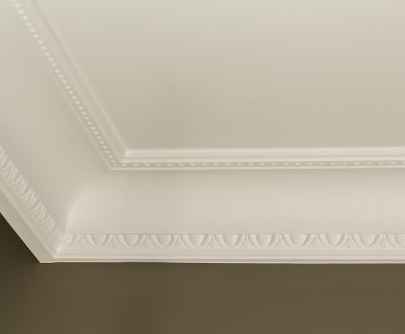 Ornamental white molding decor on ceiling of white room close-up detail. Interior renovation and construction concept.